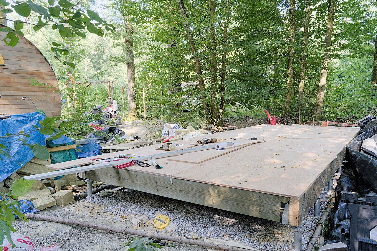 Timber floor platform sheathed with wood panels on a joist frame, tools lying on its surface