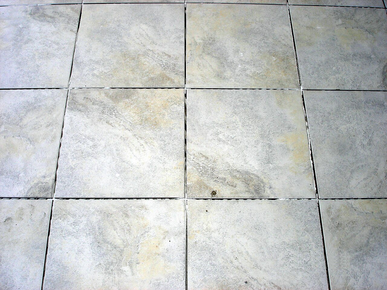 Stone-look grey ceramic floor tiles set in a straight grid with dark joints