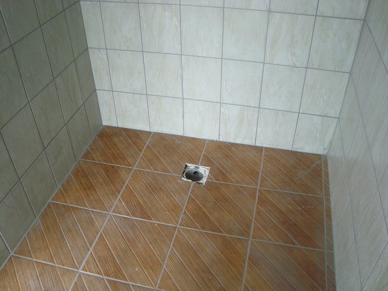 Shower floor of wood-look ceramic tiles laid on the diagonal around a central drain