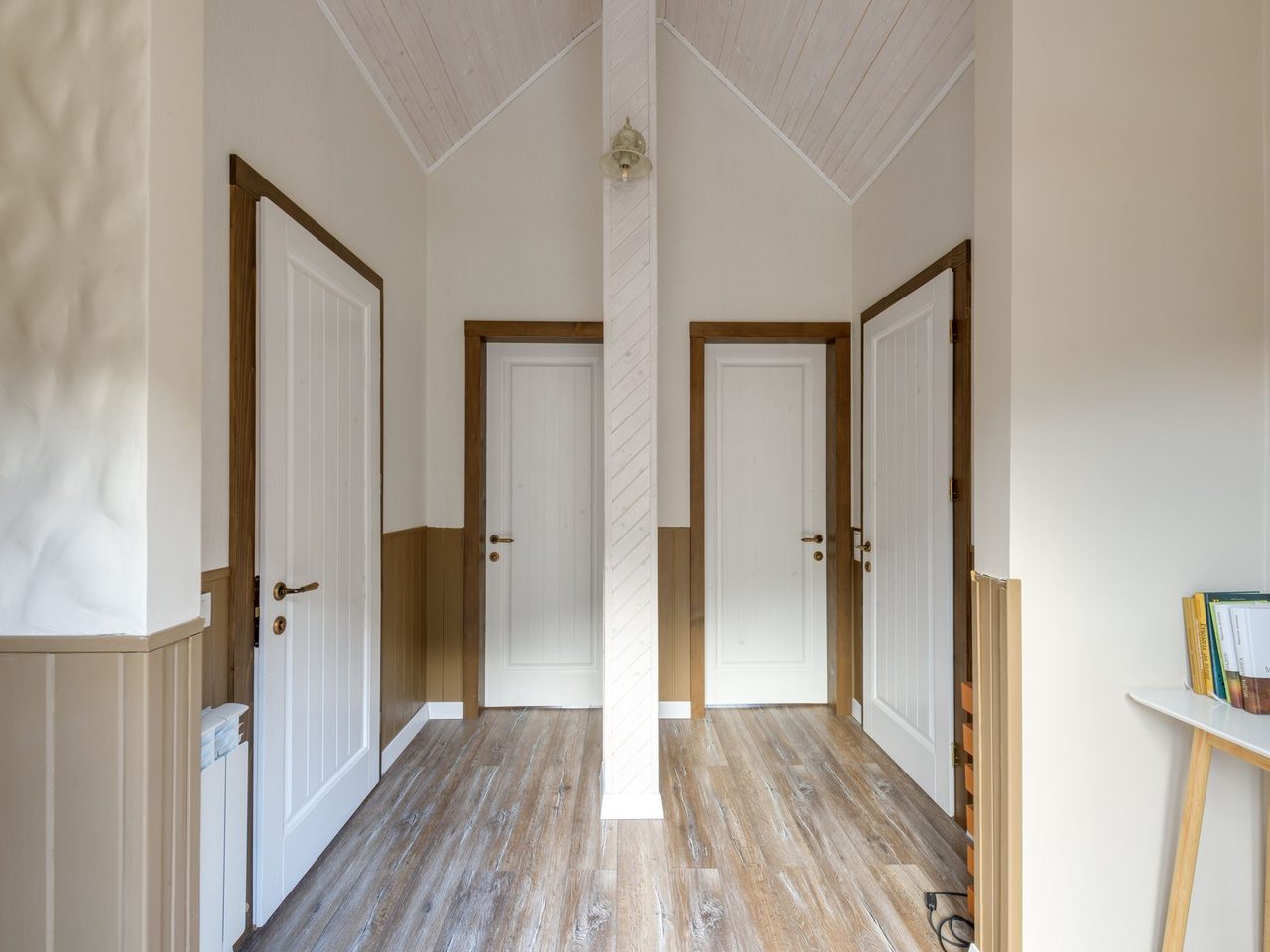 Hallway with white trimmed doors and a wood-look floor