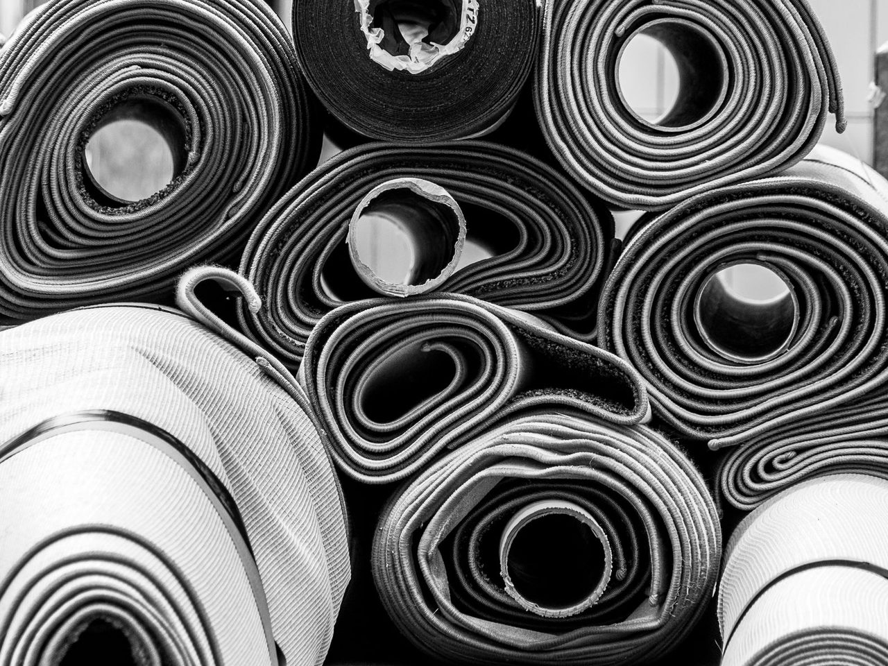 Black and white photo of rolled carpets stacked together
