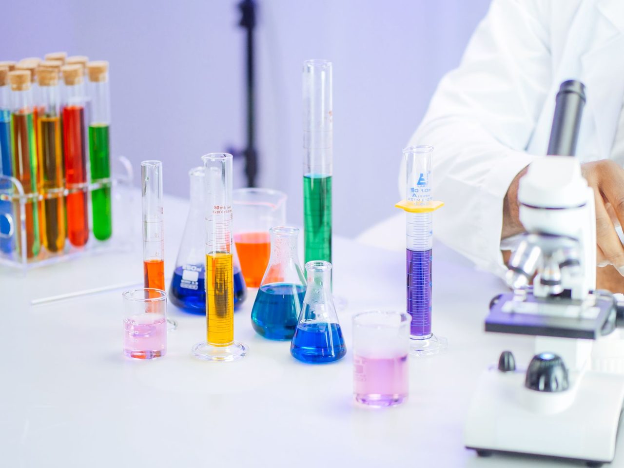 Laboratory beakers, test tubes and a microscope on a white bench
