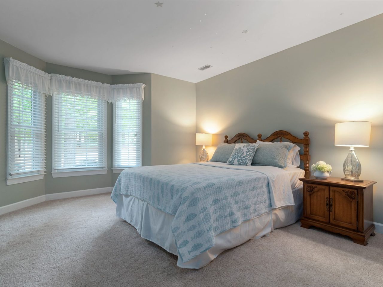 Bedroom with wall-to-wall carpet, a bed and a bay window