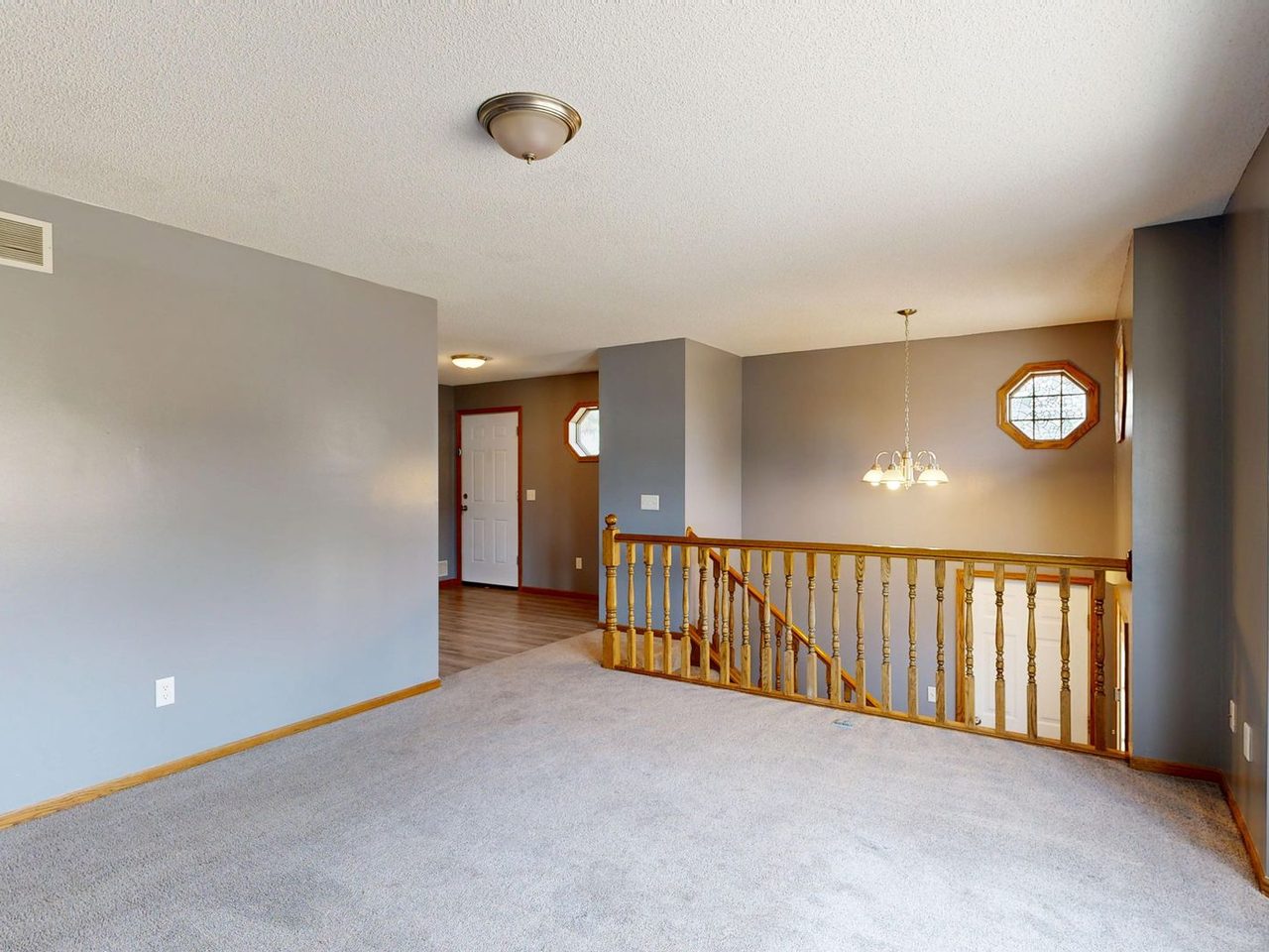 Carpeted upstairs landing beside a staircase with windows