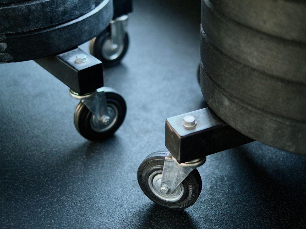 Close-up of equipment casters resting on a dark rubber floor