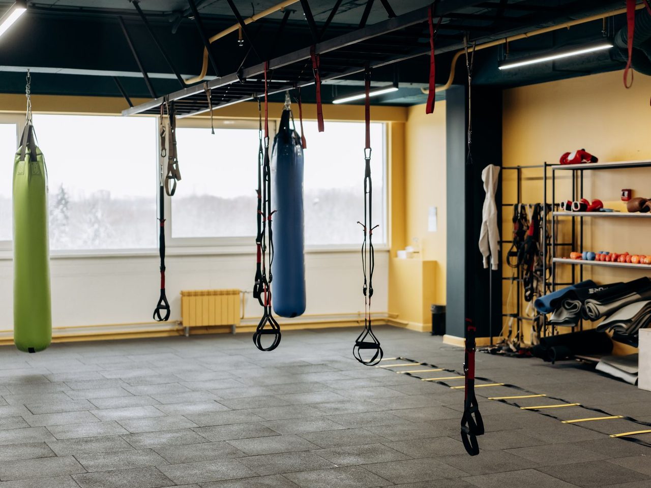 Gym interior with punching bags and a gray rubber tile floor