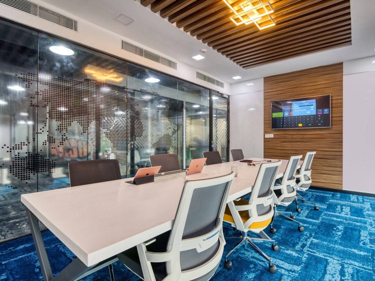 Boardroom with a long table, white chairs and blue patterned carpet