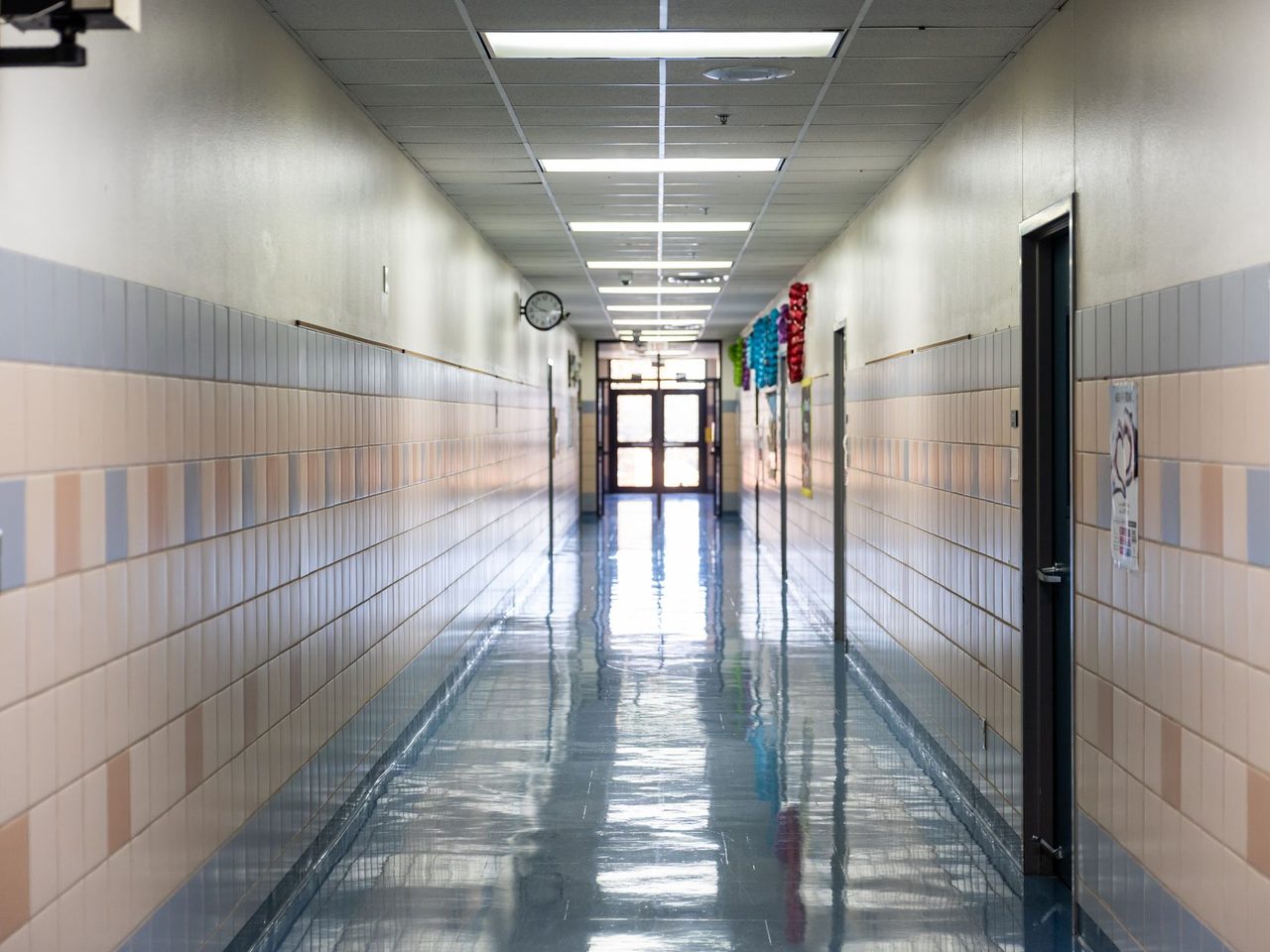 School hallway with tiled walls, fluorescent lights and a glossy resilient floor