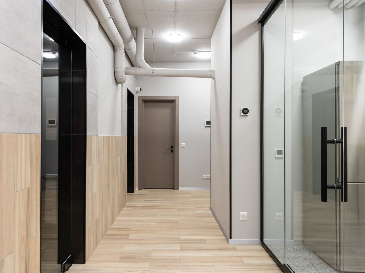 Office corridor with glass doors, gray walls and a wood-look floor