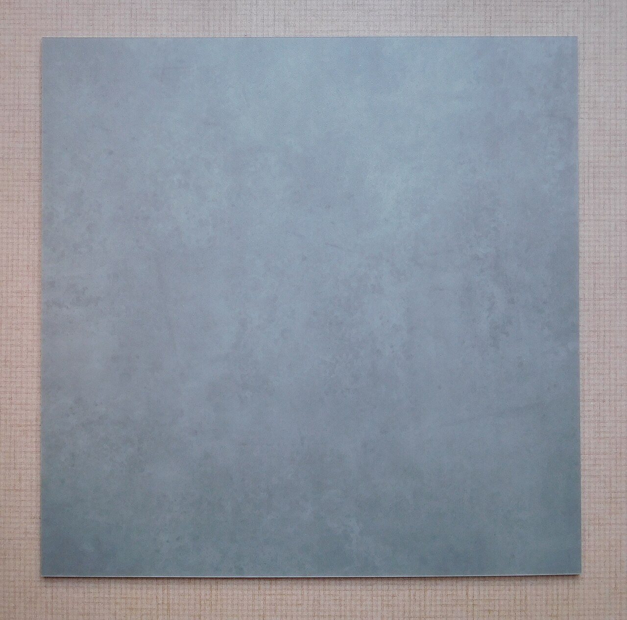 Single grey concrete-look loose-lay vinyl floor tile on a textured background