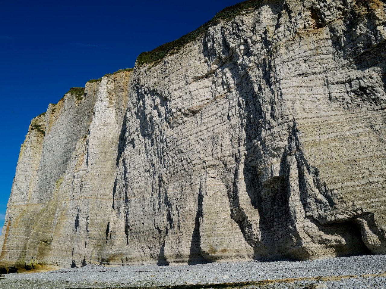 Tall layered limestone cliffs under a clear blue sky
