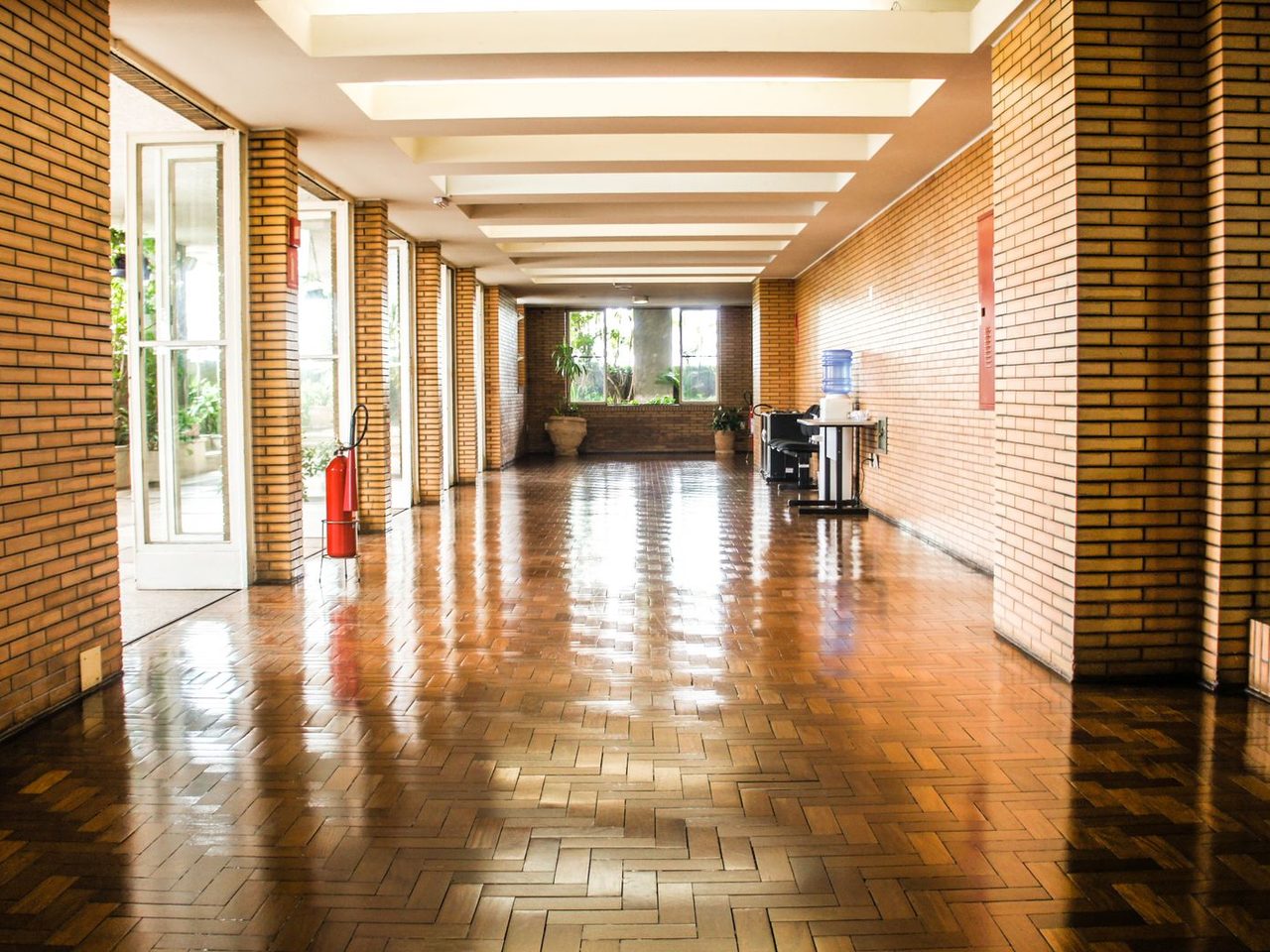 Brick-walled corridor with a polished tile floor reflecting the light