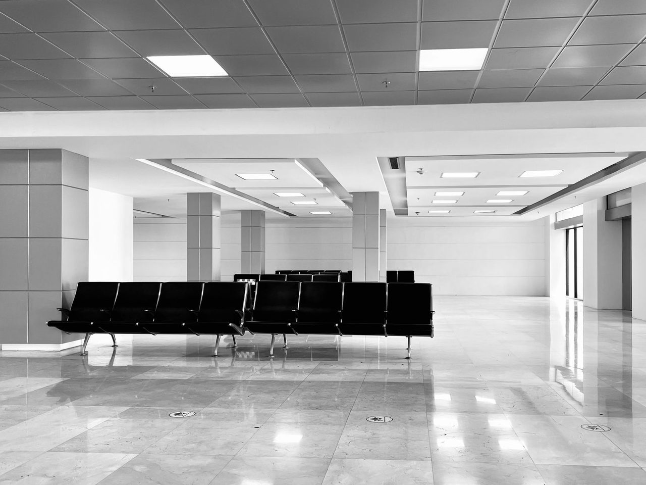 Waiting area with rows of black chairs on a glossy white tile floor