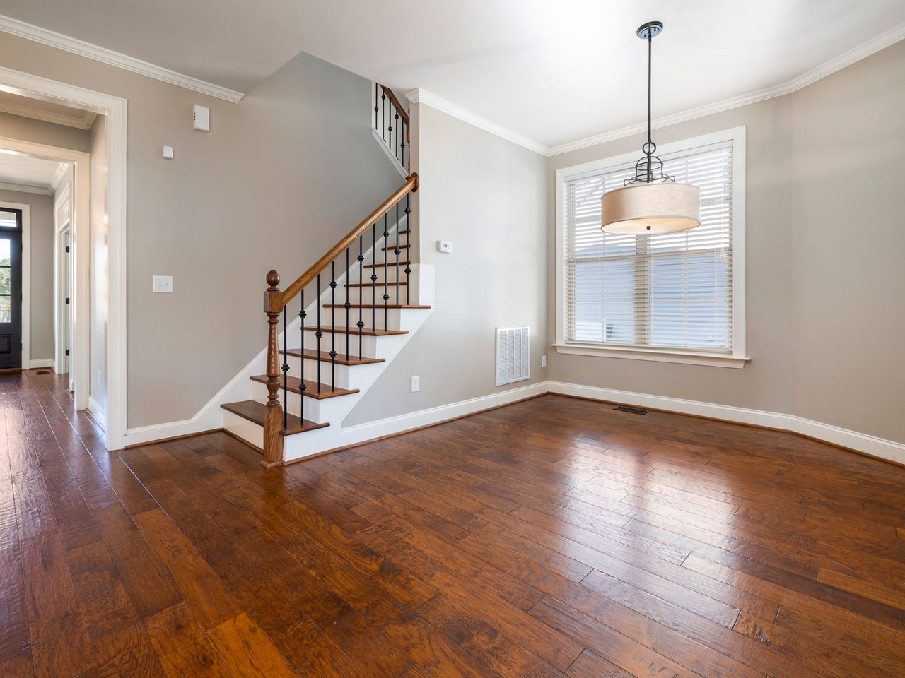 Room with a glossy hardwood floor, a staircase and a pendant light