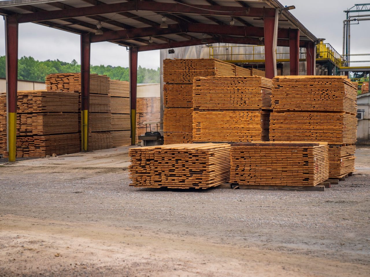 Stacks of sawn timber under a shed at an outdoor lumber yard