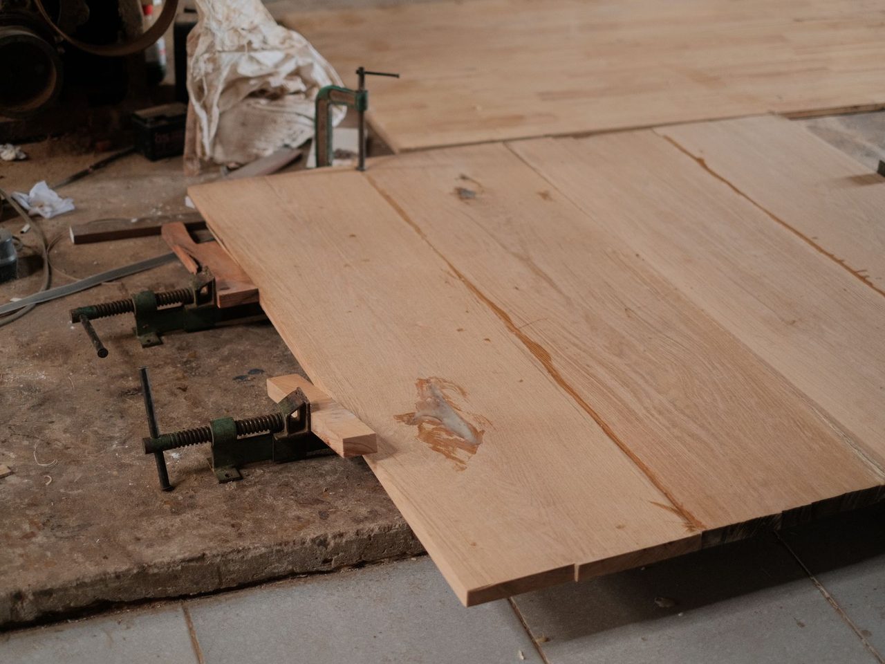 Light wood planks held with clamps on a workshop bench