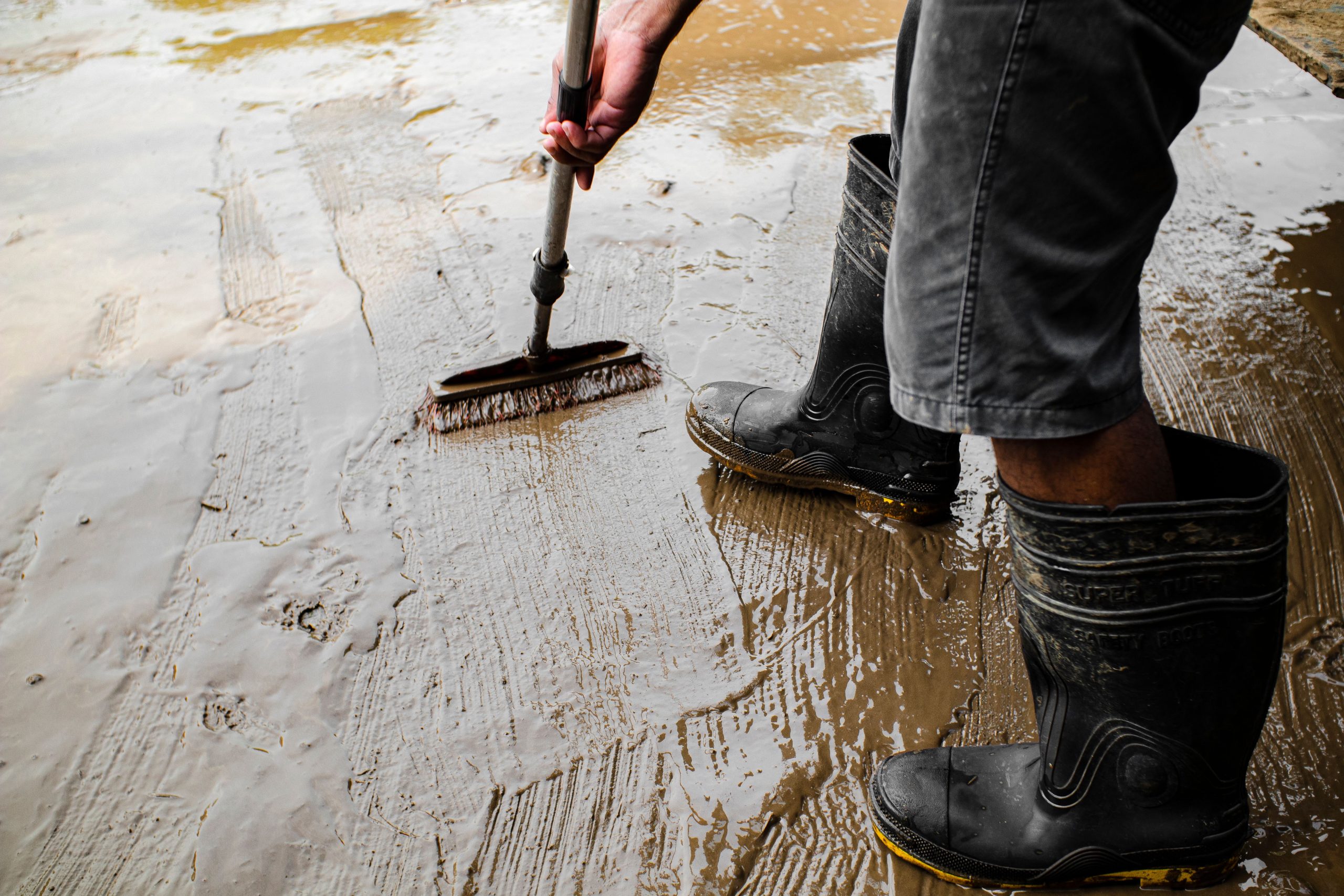 Worker priming a cement floor before self-leveling underlayment