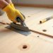 Repairing subfloor issues before tile installation with scraper and leveling tools on a plywood subfloor