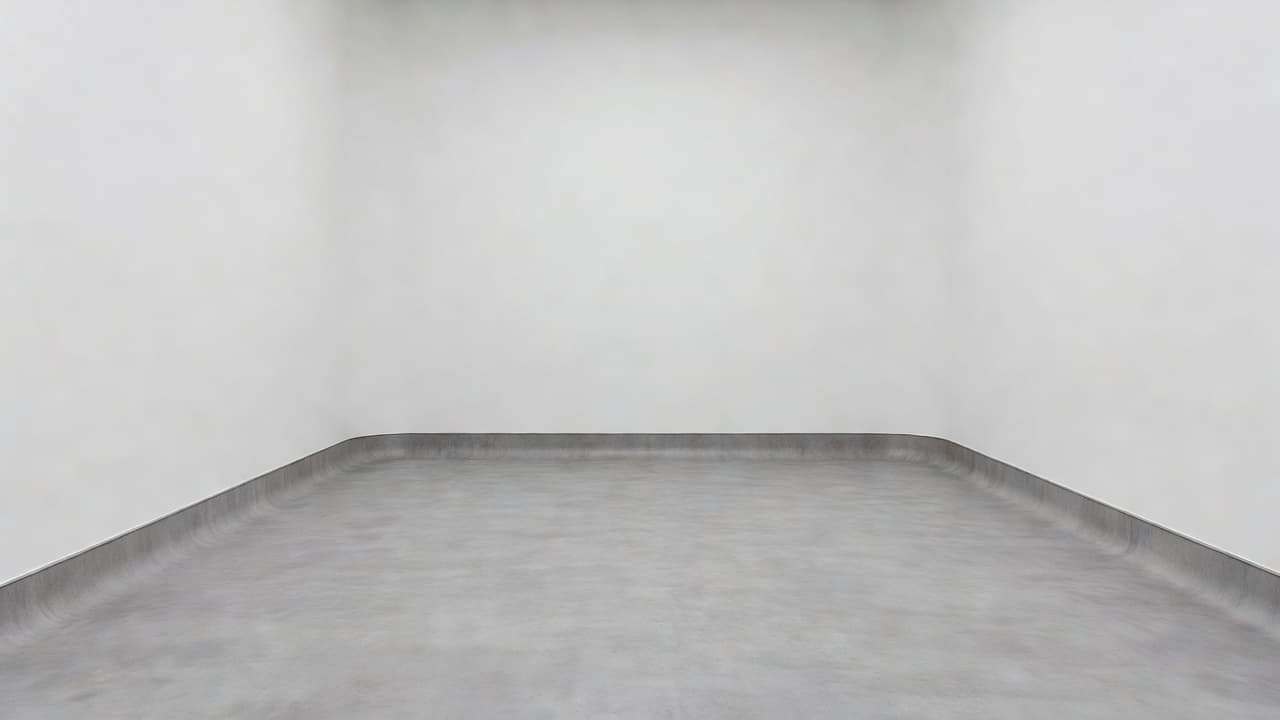 A seamless cove base installation connecting a white wall to a grey floor in a clean medical room.