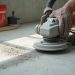 Grinding high spots on uneven concrete slab to prepare flatness for LVP flooring installation