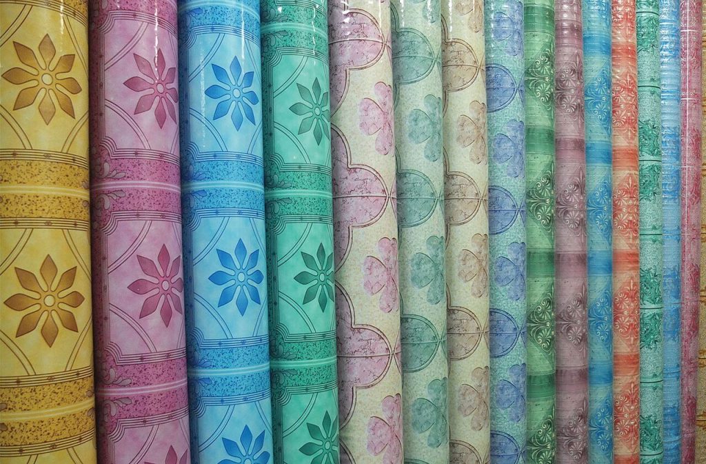 Rolls of sheet vinyl with floral and tile-style patterns in yellow, pink, blue and green on display
