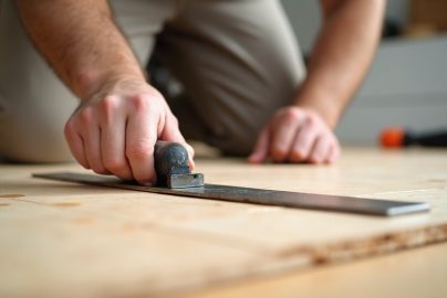 Installer checking subfloor seam flatness with a straightedge before installing LVP flooring