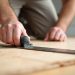 Installer checking subfloor seam flatness with a straightedge before installing LVP flooring