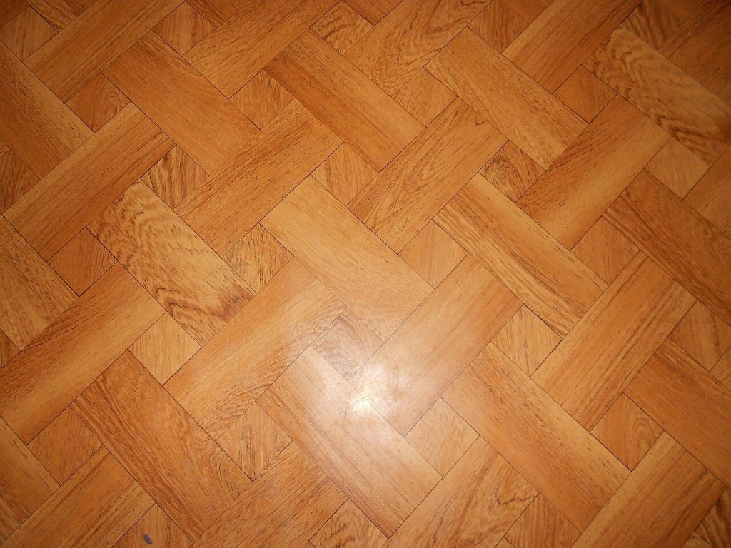 Close-up of a wood-pattern resilient sheet floor printed in a basket-weave design, with light glare
